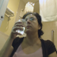 An older, mature woman wearing glasses drinks some water, pisses (with visible piss stream), and then finally takes a shit while sitting on a toilet. Audible poop sounds, but no product is seen. Presented in 720P HD. Over 4 minutes.